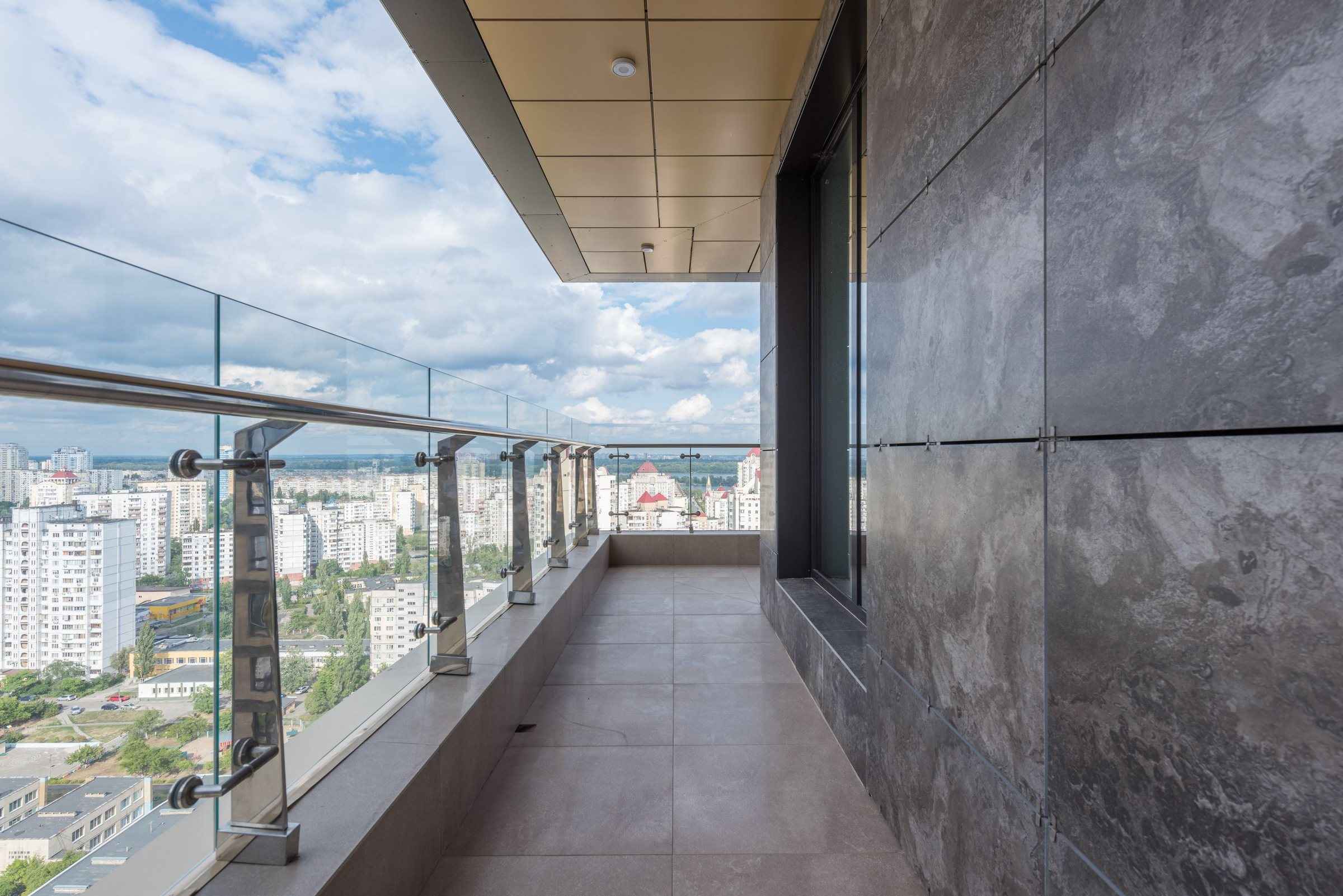 Apartman terasında paslanmaz küpeşte ve cam dolgulu korkuluk